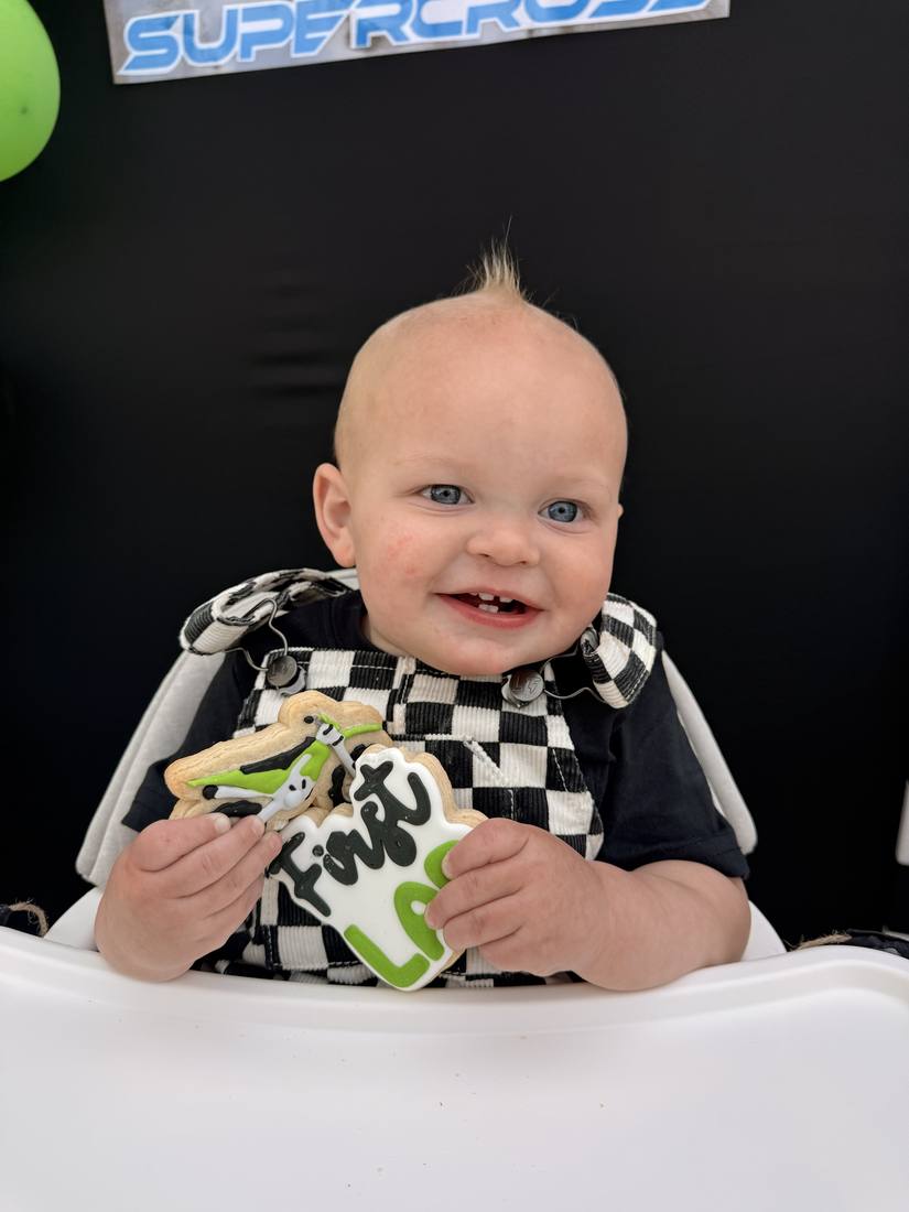 Baby holding a motocross themed first birthday cookie