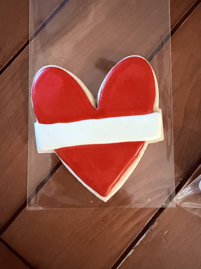Single red heart cookie with white ribbon detail