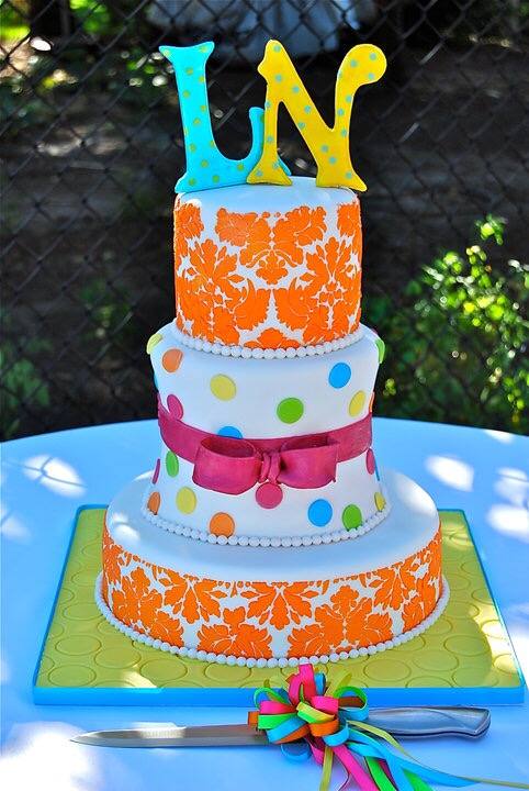 Bright orange and polka dot birthday cake with bow and letter toppers