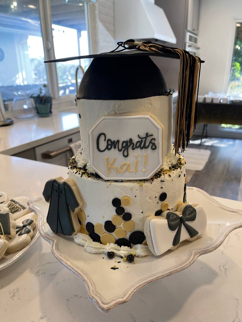 Black and gold graduation cake with cap gown and diploma cookies