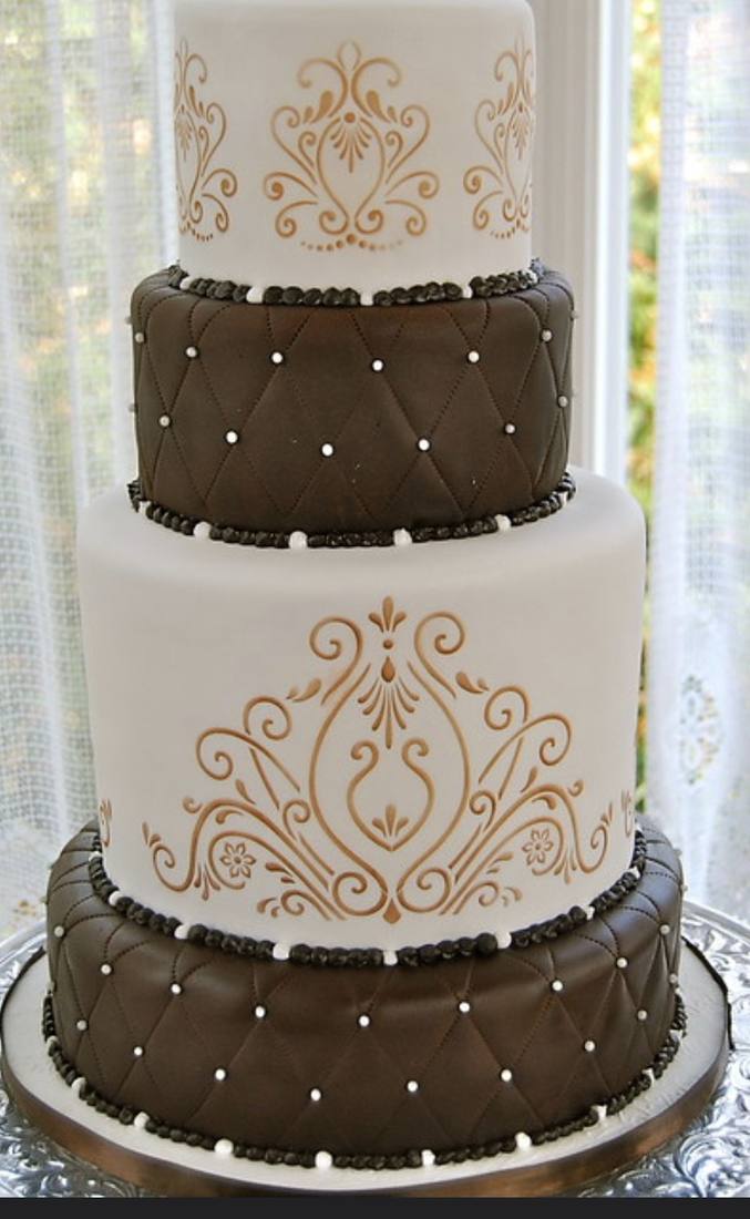 Brown and white wedding cake with a gold damask stencil design