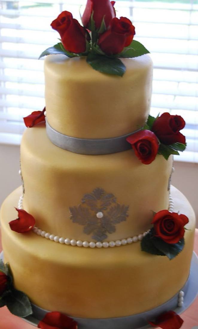 Gold fondant wedding cake with red roses and a damask stencil