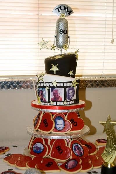 80th birthday cake with a sculpted microphone, film strip and photo cookies