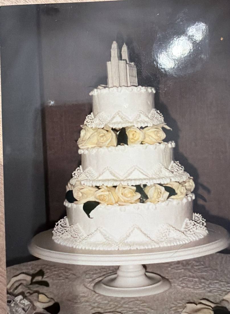 Four tier white lace wedding cake with cream roses and a temple topper